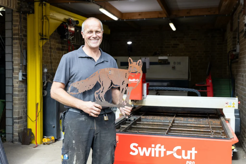 Gert Martens using his Swift-Cut Pro CNC plasma cutting table holding metal cut out of a fox