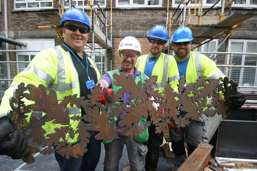 DIY SOS The Big Build team holding piece of beautiful garden pergola with Oak leaf design on a roof space at the Great Ormond Street Hospital cut by Nigel Ferguson Fabrications on the Swift-Cut Pro CNC plasma cutting machine