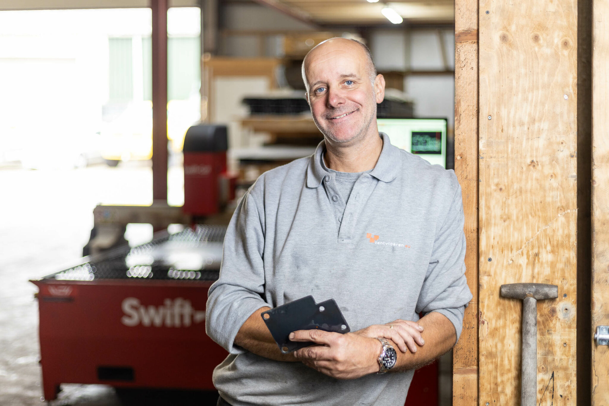 Peter, representing Tentvloeren, standing in front of his Swift-Cut Pro CNC plasma cutting table holding metal pieces he cut out on the table