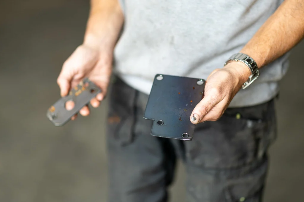 Peter, representing Tentvloeren, holding metal pieces he cut out on the table